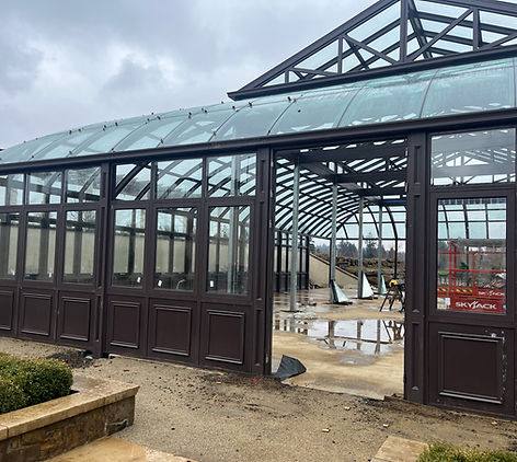 Entrance archway of the Arboretum showing the glass roof and dark metal framework