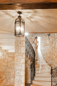 Bride ascending an ornate wrought-iron staircase beneath a lantern