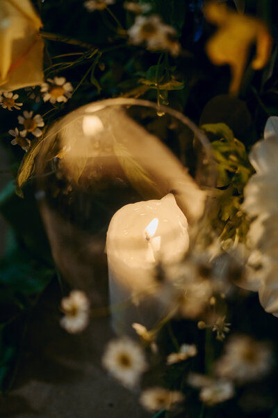 Candlelit floral arrangement glowing softly among white blooms at dusk