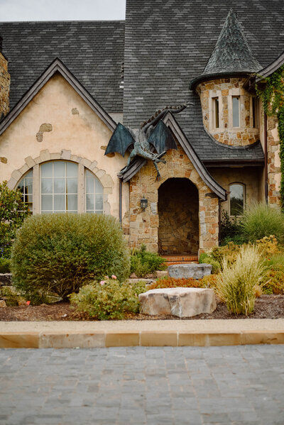 Chateau exterior showing its tan stucco walls, stone archway entrance and dragon roof ornament