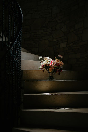 Hand-tied floral arrangement resting on a dimly lit stone staircase