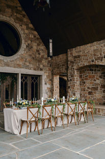 Long reception table set beneath a soaring stone gable with a round window