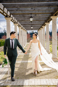 Bride and groom walking hand in hand beneath a colonnaded pergola